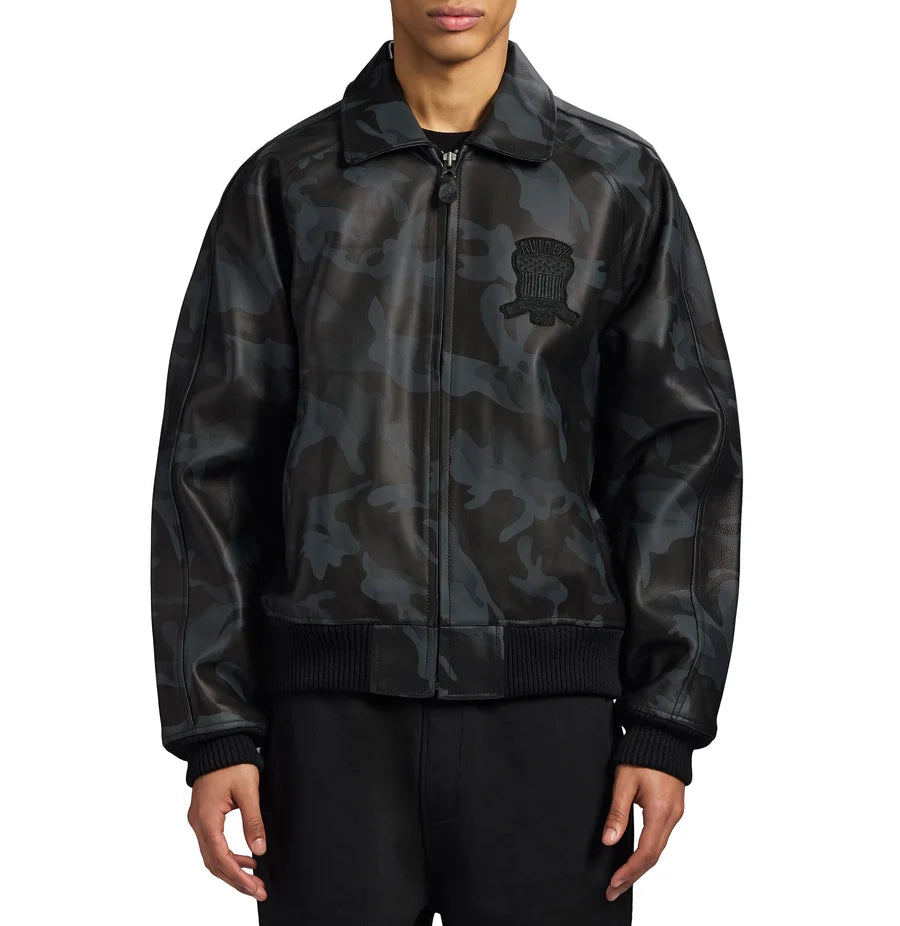 Men's AVIREX black camouflage leather bomber jacket front view with zip closure, chest emblem, side pockets, and ribbed cuffs.