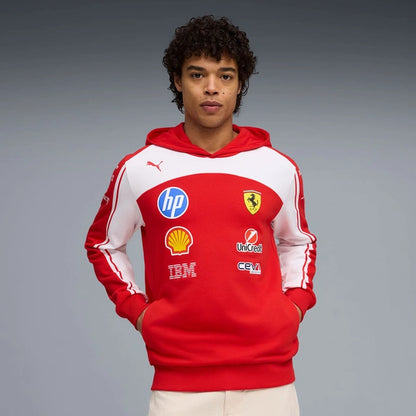 Person wearing a red hoodie with various logos on a gray background