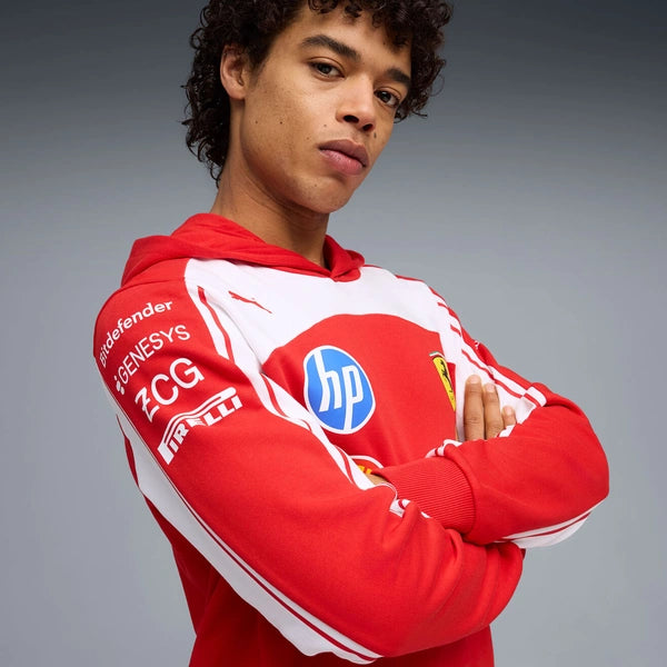 Person wearing a red hoodie with multiple logos on a gray background