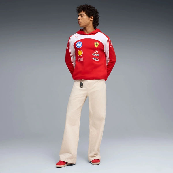 Person wearing a red and white hoodie with various logos on a gray background