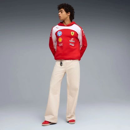 Person wearing a red and white hoodie with various logos on a gray background