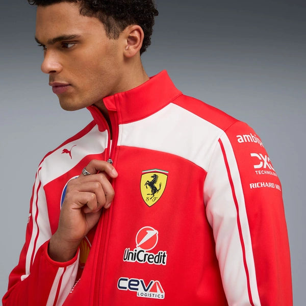 Person wearing a red and white jacket with various logos, including Ferrari, on a gray background.