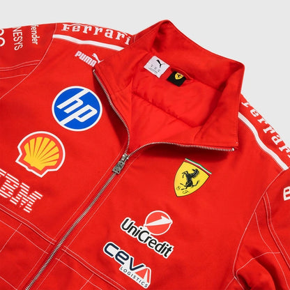 A close-up of a red Ferrari team jacket featuring white piping, sponsor logos including HP, Shell, UniCredit, and Puma, and the Scuderia Ferrari prancing horse crest.
