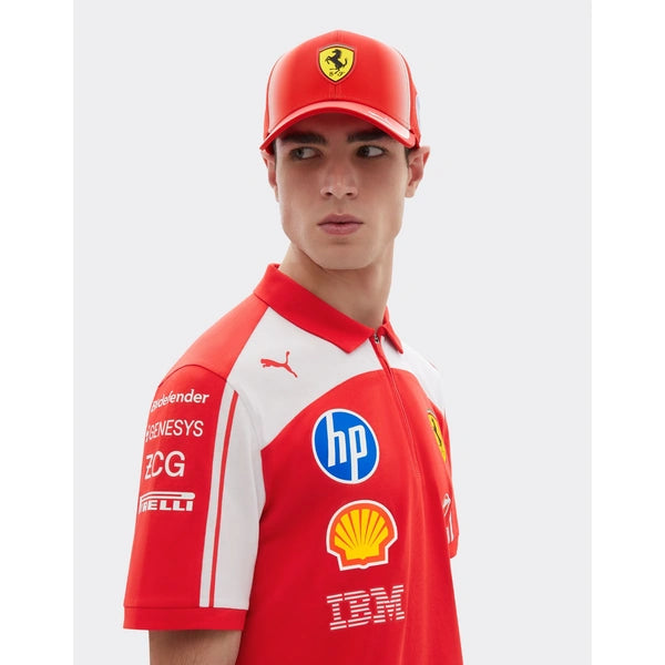 A man wearing a red and white Ferrari team polo shirt with sponsor logos and a matching red cap featuring the Ferrari prancing horse, photographed against a light gray studio background.