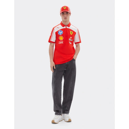A man modeling a red and white Scuderia Ferrari short-sleeve polo shirt with various sponsor logos, paired with dark gray jeans, a red Scuderia Ferrari cap, and white sneakers, set against a plain light gray background.
