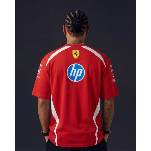 A man viewed from behind wearing a red Ferrari team t-shirt with white side stripes, featuring the HP logo on the back, set against a dark studio background.