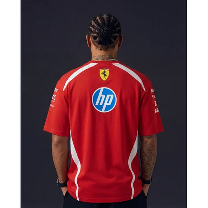 A man viewed from behind wearing a red Ferrari team t-shirt with white side stripes, featuring the HP logo on the back, set against a dark studio background.