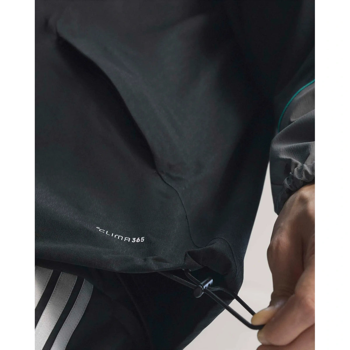 Mercedes AMG Petronas F1 black racing jacket worn by model with hood and teal motorsport accents