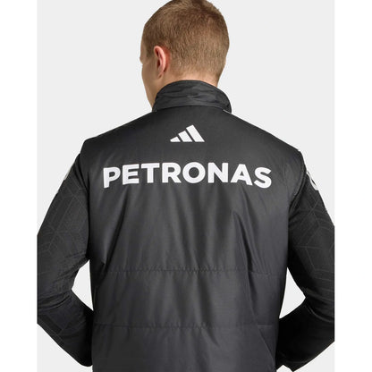 Rear view of a man wearing a black Adidas jacket with large white PETRONAS branding on the back, against a light gray background.